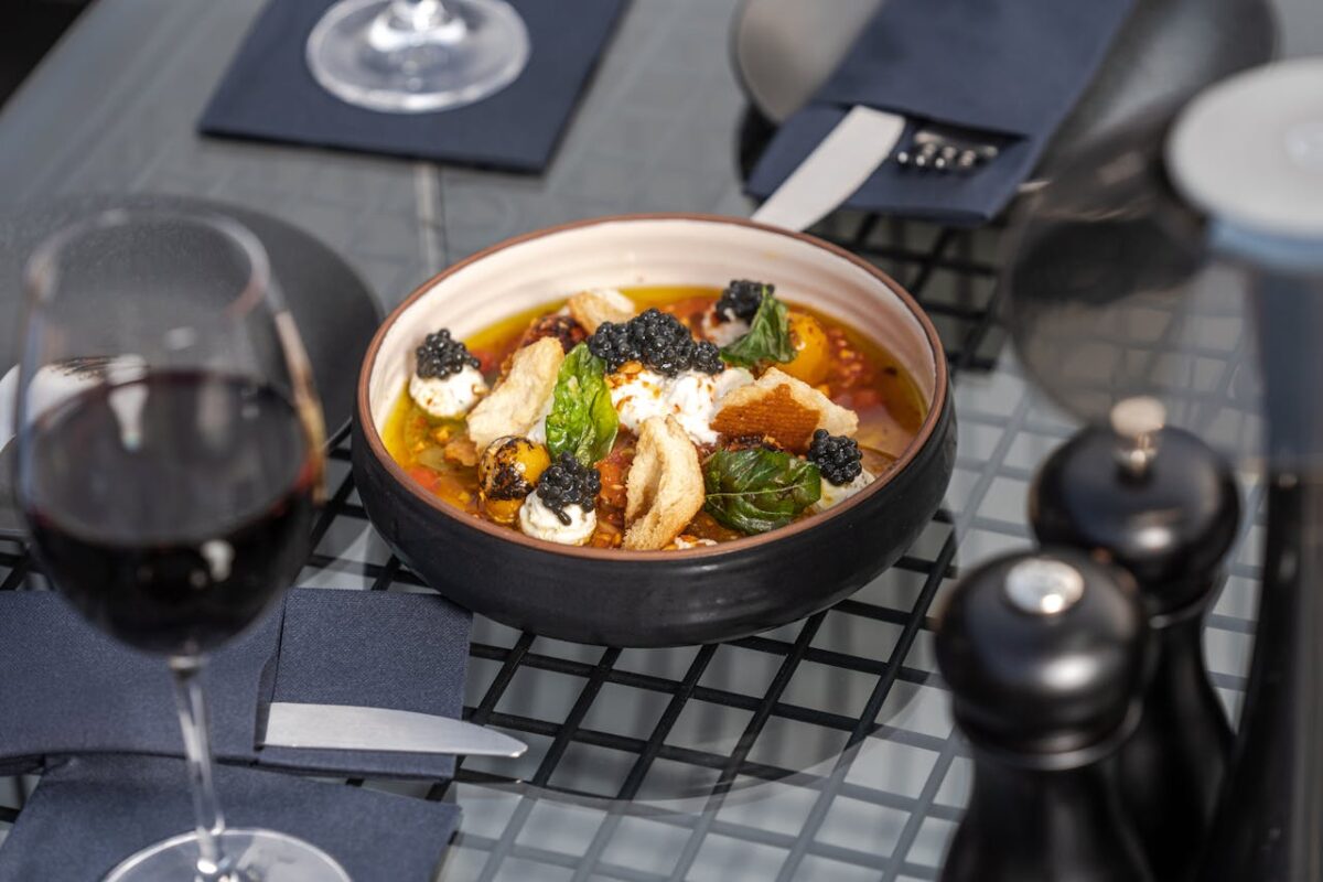 Luxurious gourmet dish with caviar served on a glass table next to red wine in Dubai.